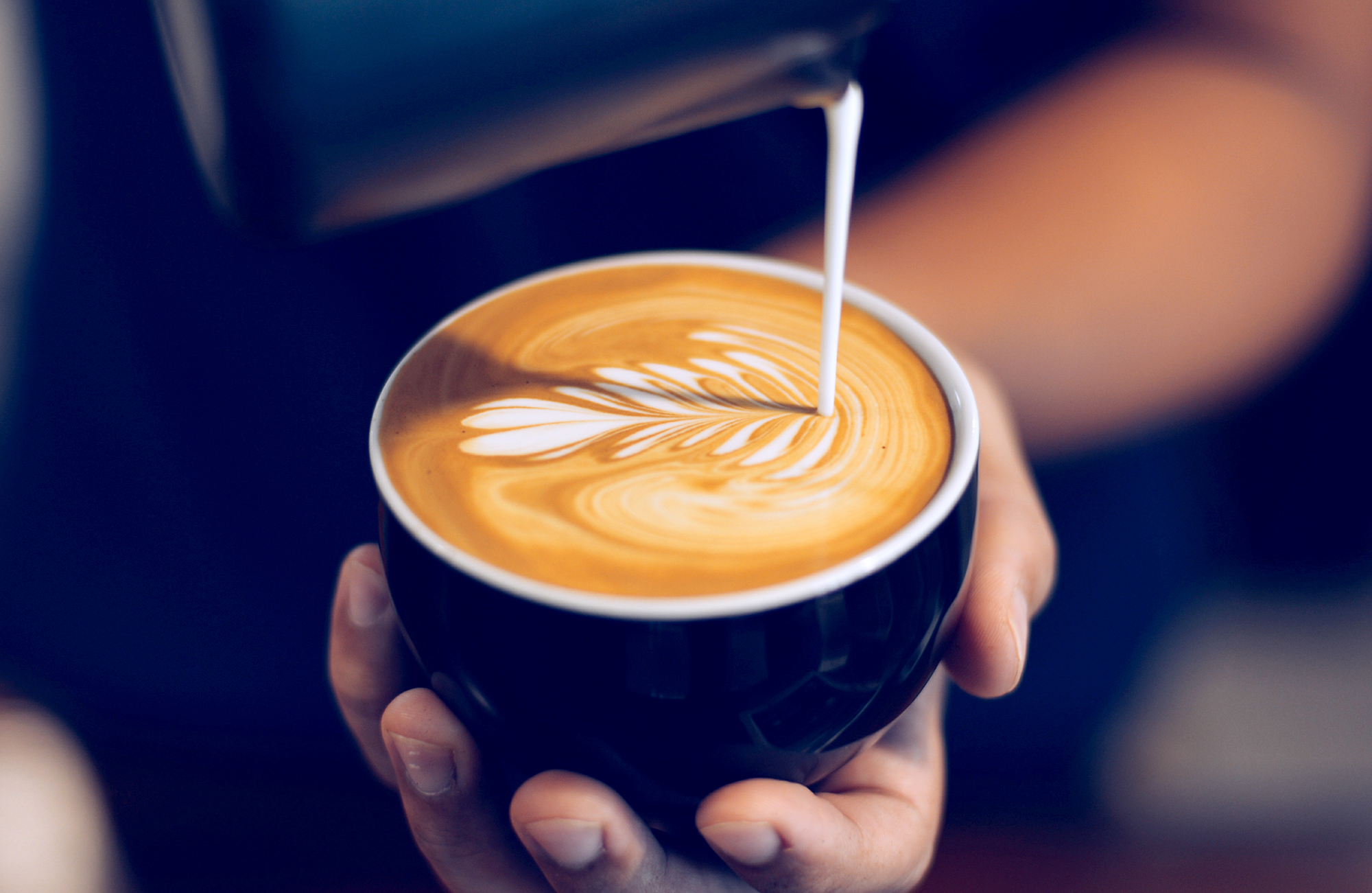 A barista pours a latte.